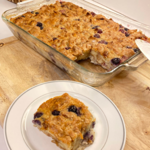 A baking dish with triple berry bread pudding and a small plate with a piece of the triple berry bread pudding.