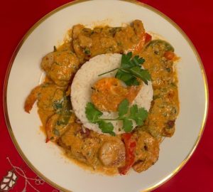 A plate ( brazilian moqueca seafood, bell peppers, fish, scallops, shrimp , tomato paste, onions, garlic in coconut broth