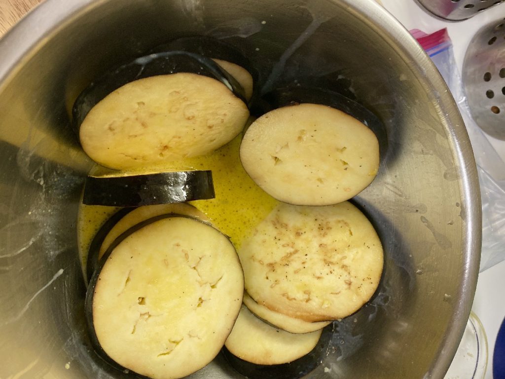 A large bowl with eggplants cut into discs 